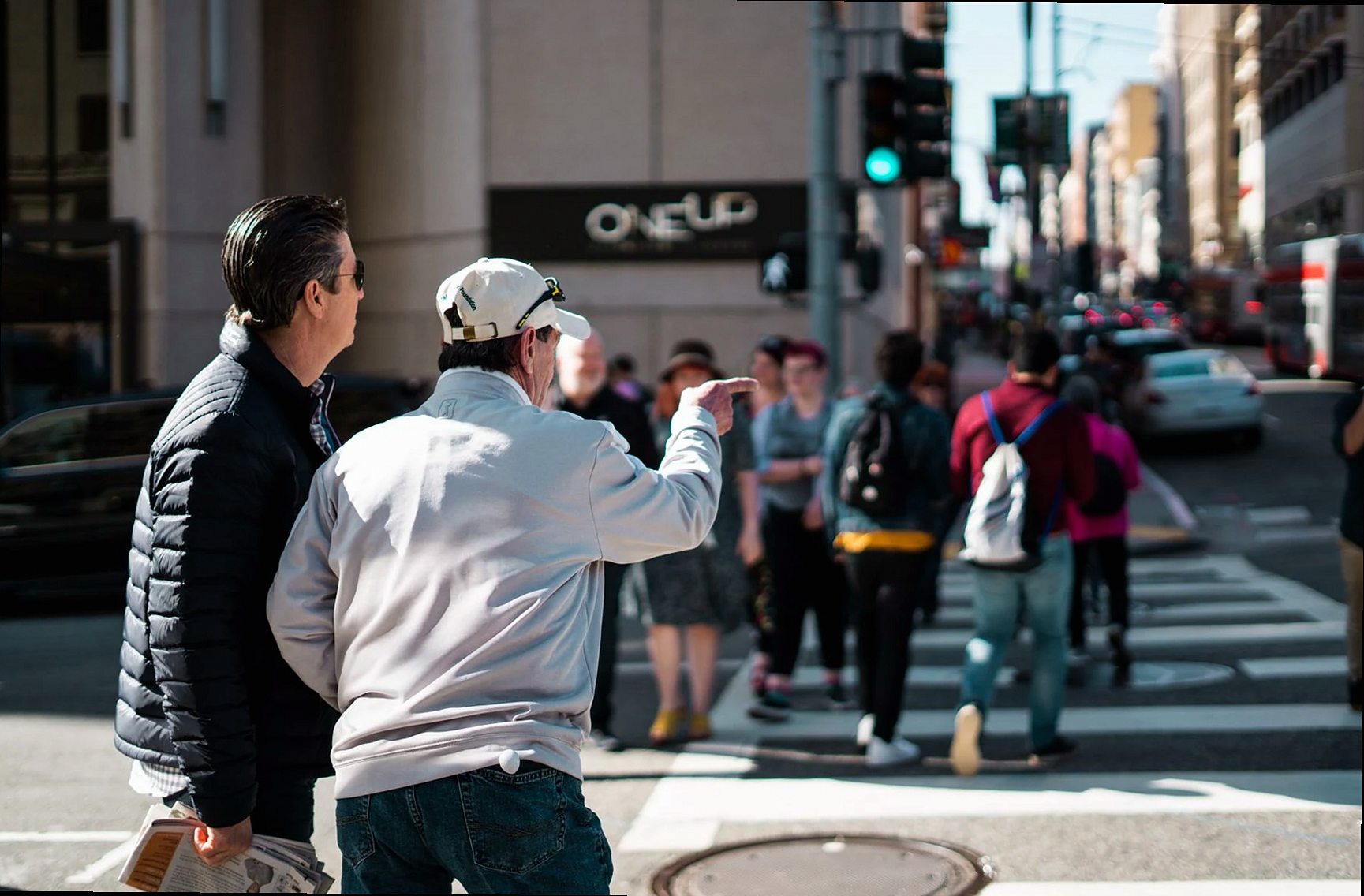 Personas cruzando una calle urbana en una concurrida intersección durante el día.